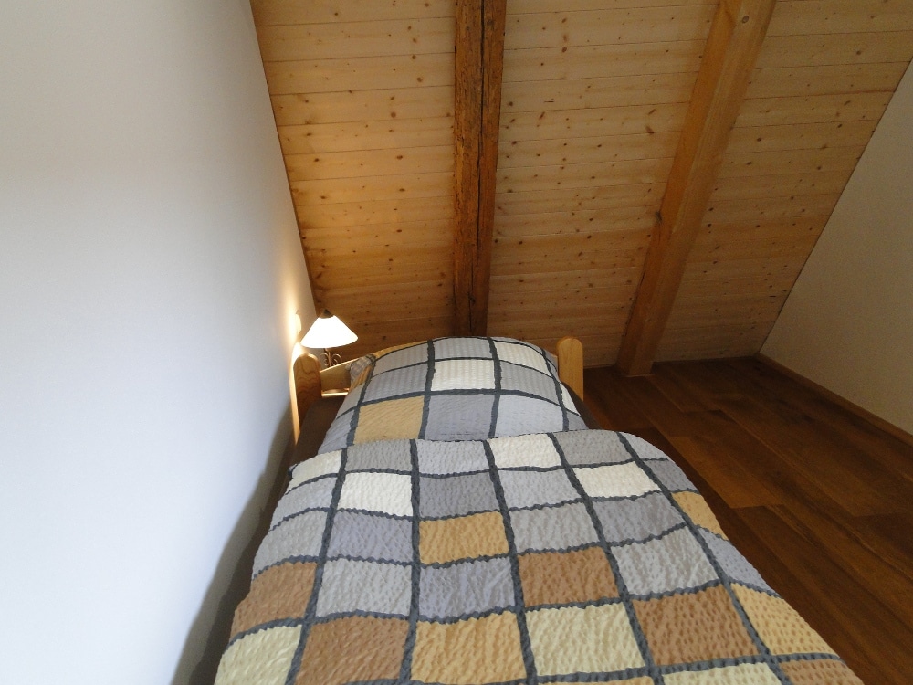 Einzelbett längs an der Wand mit Nachttisch am Kopfende